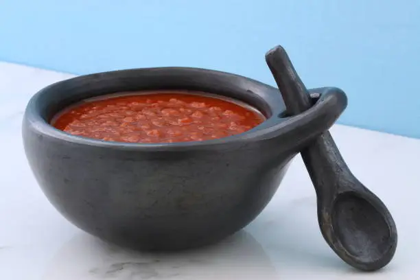 Artisan mexican red hot sauce on retro vintage carrara marble in beautiful terracotta pot, perfect for all your Mexican, tex-mex recipes and sides.