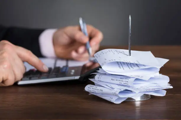 Photo of Businessman Calculating Invoice Using Calculator