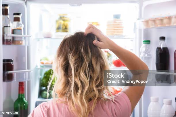 Mujer Confundida En El Refrigerador Abierto Foto de stock y más banco de imágenes de Frigorífico - Frigorífico, Alimento, Mujeres