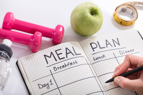 filling meal plan in notebook at wooden desk