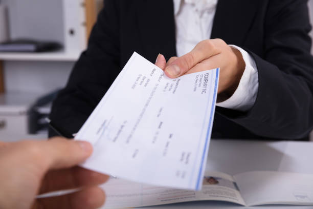 Business Woman Handing Over Cheque To Her Colleague Close-up Of A Business Woman Handing Over Cheque To Her Colleague At Workplace bowie seamount stock pictures, royalty-free photos & images