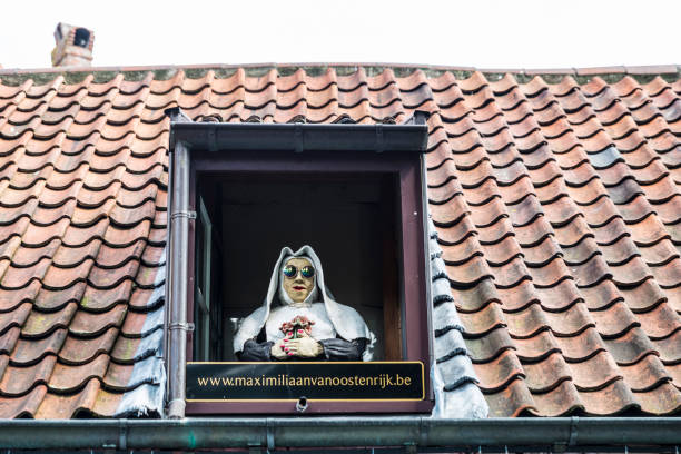 Bruges, Belgium - September 1, 2017: Nun statue with sunglasses on the window of a roof as advertising for a restaurant bar in the old historic center of the medieval city of Bruges, Belgium