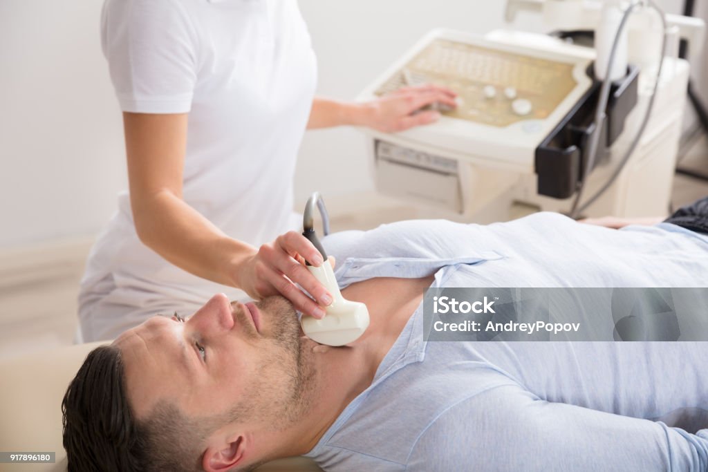 Young Man Getting Ultrasound Of A Thyroid Young Man Lying On Back Getting Ultrasound Of A Thyroid In A Clinic Men Stock Photo