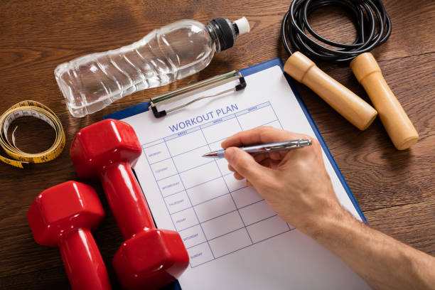istock Person Filling Workout Plan Form With Workout Equipments 917896564
