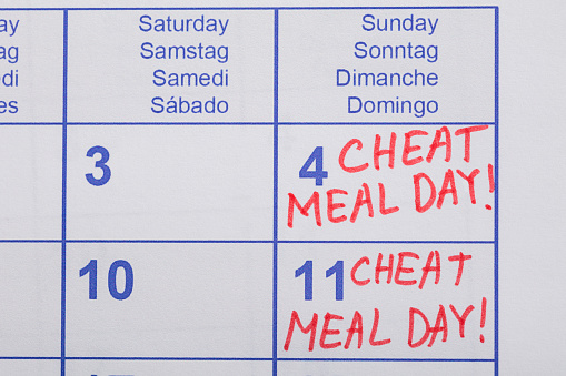 Close-up Of Cheat Meal Day Text Written On Calendar Date