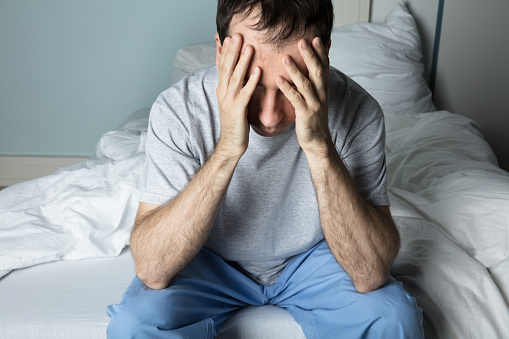 Close-up Of A Stressed Man Sitting On Bed At Home