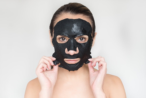 Hispanic woman with beauty mask on face made of charcoal