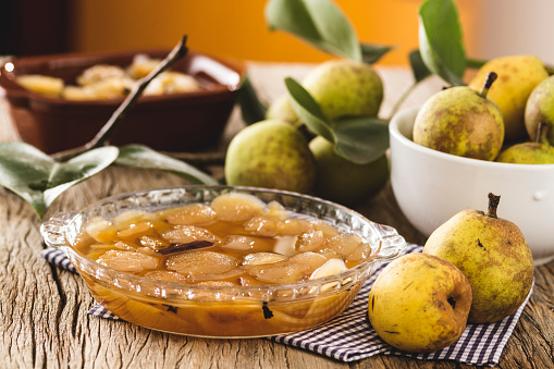 Pear compote, upon a wooden surface, with some ripe pears spread around.