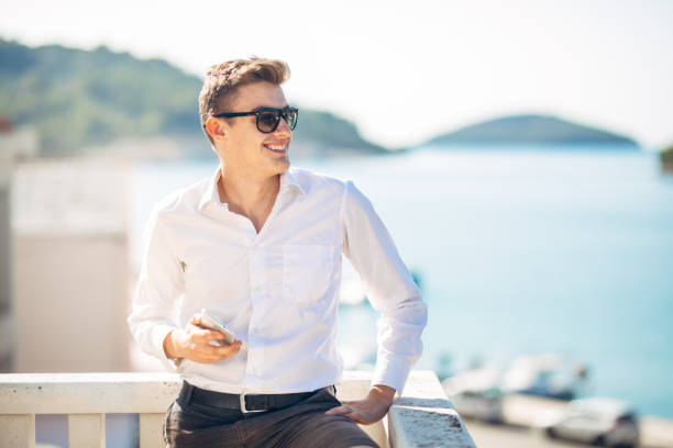 Young handsome man enjoying stay at luxury resort hotel with panoramic view on the sea.Smiling cheerful business man at a earned tropical vacation stock photo