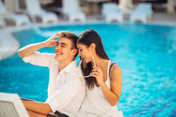 loving couple spending vacation on tropical resort swimming pool.newlyweds honeymoon on seaside.couple in true love.flirting and showing emotions. - honeymoon beach swimming pool couple imagens e fotografias de stock