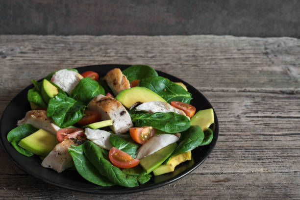 istock Chicken salad with avocado, spinach and tomatoes cherry in black plate 917919246