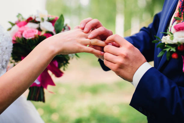 istock groom puts a wedding ring on the bride's finger 917928896