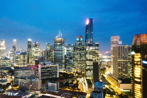 Singapore City, Singapore - 2nd December 2022: Dawn breaking over the central business district and Marina Bay in Singapore with Singapore cricket club in the foreground