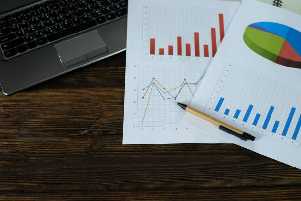 istock Notebook laptop computer and financial graph on white paper on working table, business planning vision and finance analysis concept. 917937646