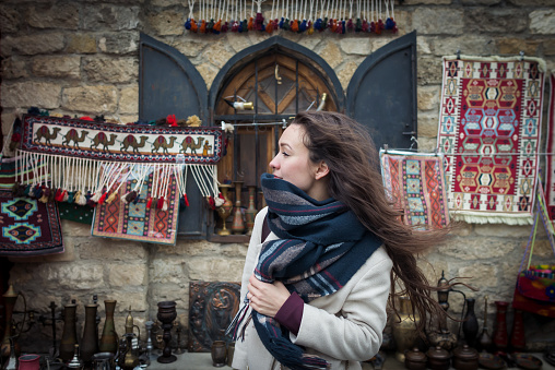 Curious traveler explores authentic oriental bazaar in Central Asia in winter season. Young woman stands near a beautiful showcase on the eastern market. Cheerful person traveling in old town