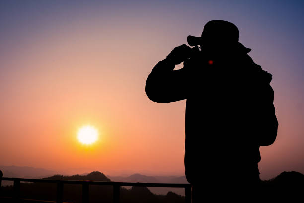 istock Silhouette Handsome man looking forward with binoculars at a mountain and drinking coffee 917955334