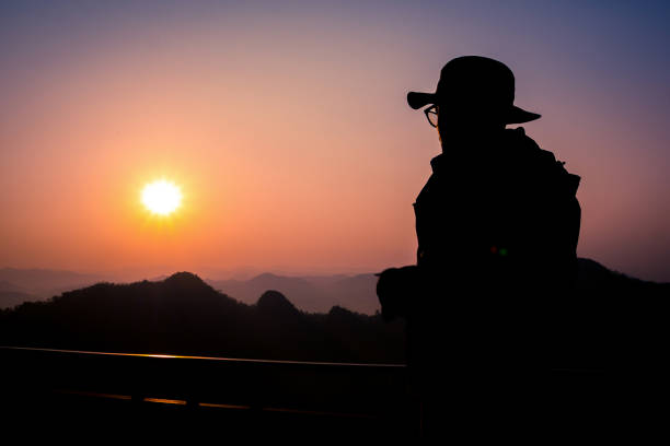 istock Silhouette Handsome man looking forward with binoculars at a mountain and drinking coffee 917955338