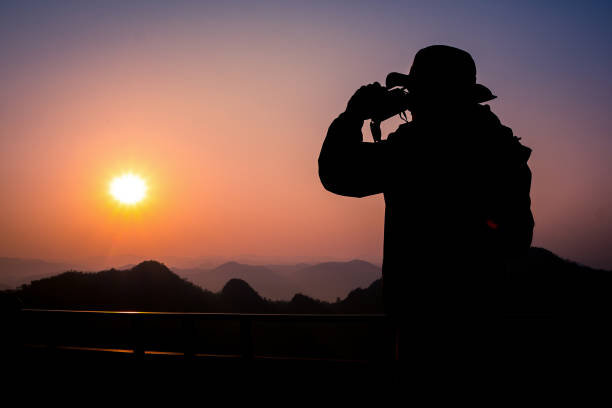 istock Silhouette Handsome man looking forward with binoculars at a mountain and drinking coffee 917955340