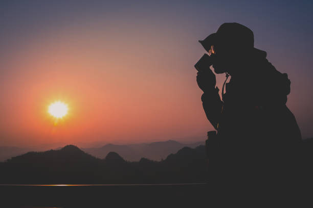 istock Silhouette Handsome man looking forward with binoculars at a mountain and drinking coffee 917955348