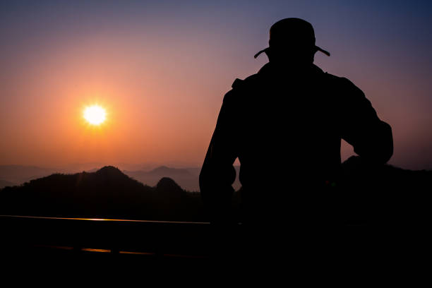 istock Silhouette Handsome man looking forward with binoculars at a mountain and drinking coffee 917955350