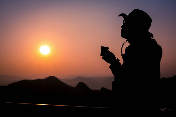 istock Silhouette Handsome man looking forward with binoculars at a mountain and drinking coffee 917955356