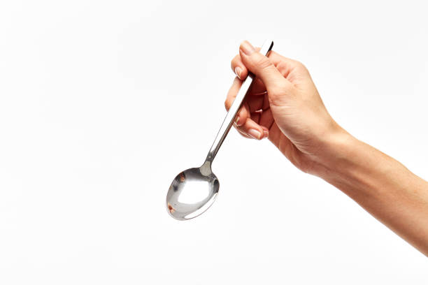 istock woman's right hand holds a spoon on a white background. 917987712