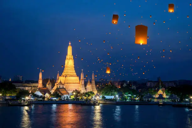 Wat Arun temple on night in Bangkok city with yeepeng float lantern background, this immage can use for Thailand travel and new year celebration in Thailand.