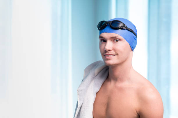 Young man wearing a swimming cap with swimming goggles copy space