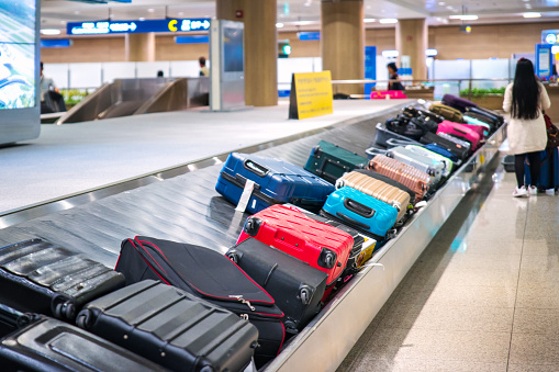 Traveler waiting for a travel bag on the belt in airport after arrival to airport destination flight