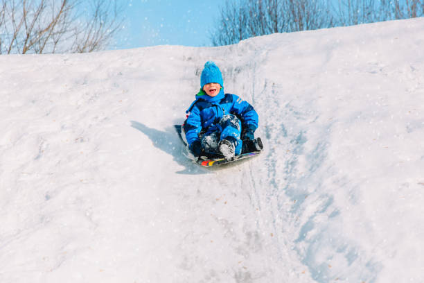 istock kids winter fun- little boy sliding in snow 918008110