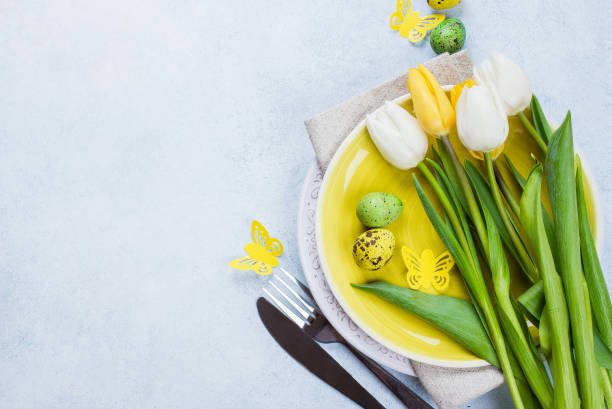istock Easter table setting with spring tulips, quail eggs and cutlery. Spring Holidays Stone Blue background. Top view, flat lay, copy space 918008340