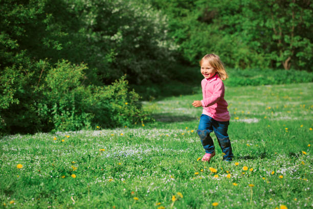 istock happy little girl run play in spring nature 918011030