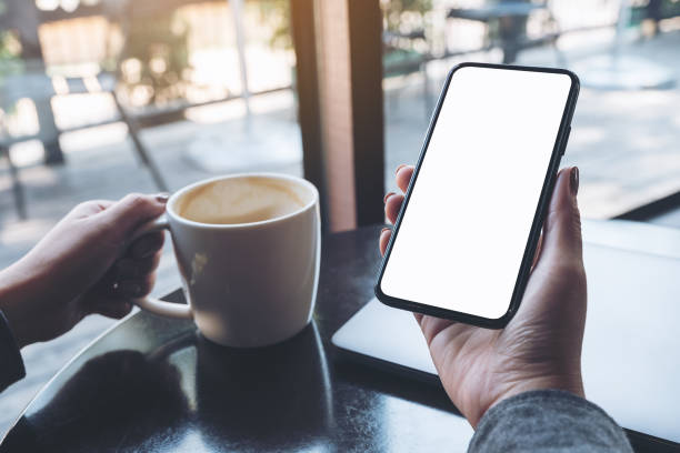 istock a woman's hand holding black mobile phone with blank white desktop screen 918011684