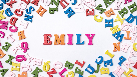 Baby name EMILY composed of wooden letters on floor.