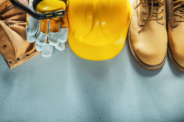 Building helmet tool belt safety gloves boots earmuffs on concre Building helmet tool belt safety gloves boots earmuffs on concrete background. helmet hardhat protective glove safety stock pictures, royalty-free photos & images