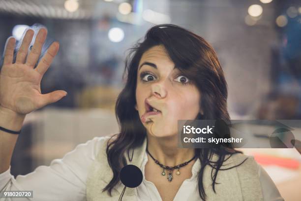 Playful Woman With Glued Face On Glass Wall Looking At Camera Stock Photo - Download Image Now