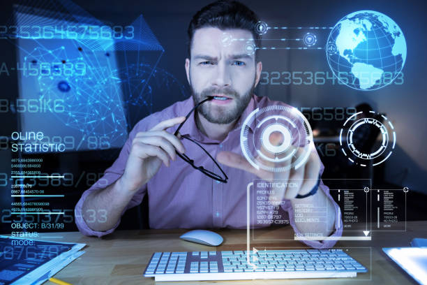 istock Smart programmer frowning while biting his glasses and pointing to the screen 918020966