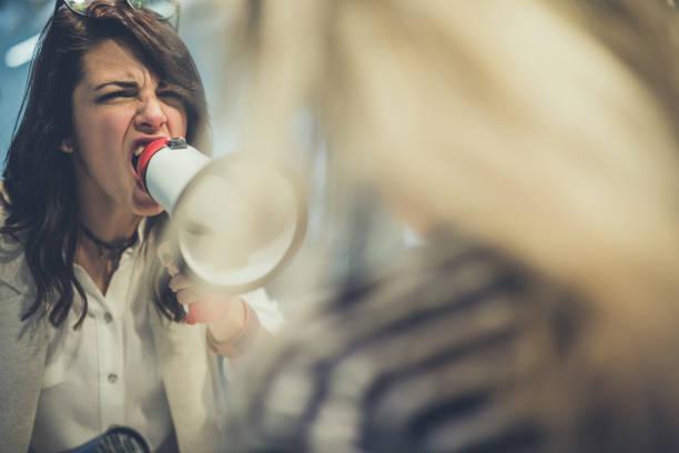 femme en colère criant à son collègue subalterne par mégaphone. - emotional stress ideas bullying office photos et images de collection