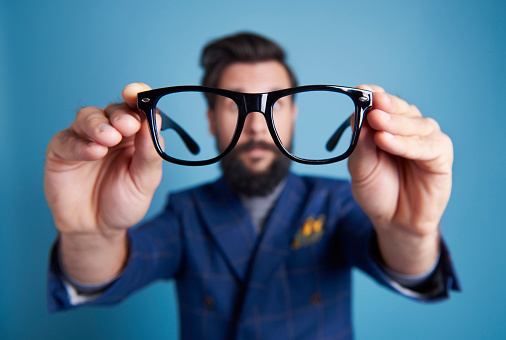 Man holding eyeglasses in front his face