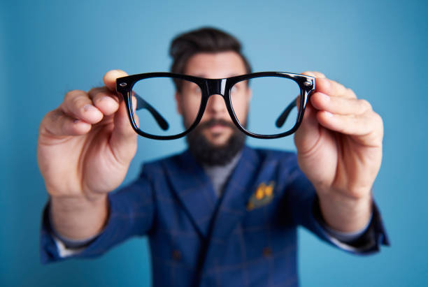 man holding eyeglasses in front his face - olhando através imagens e fotografias de stock