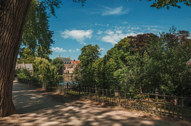 istock Path amidst greenery, lake and old brick building on the other side in Bruges. 918027406