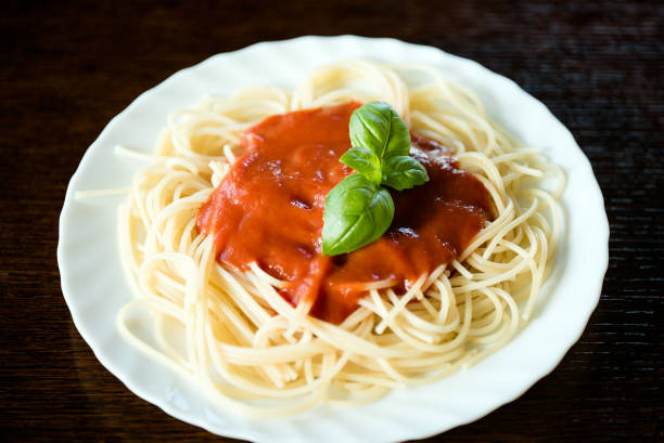 istock Italian pasta spaghetti topped with a tomato and fresh basil 918045672