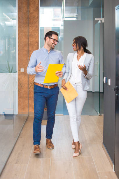 istock Two business people walking and talking at office corridor. 918046378