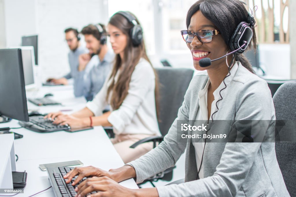 Smiling young woman with headset working in call center. Call Center Stock Photo