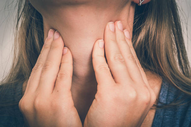 frau mit kehle wund hält schmerzende kehle - thyroid gland stock-fotos und bilder