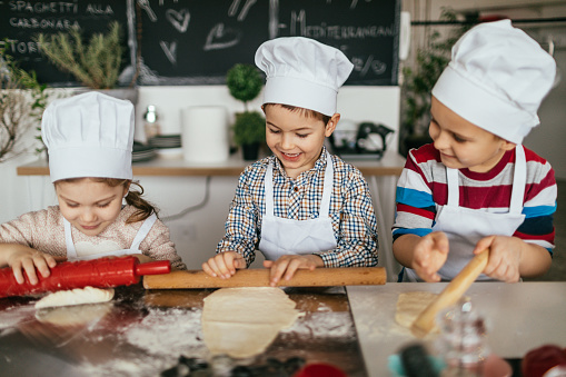 Photo of a cute little children preparing food in the kitchen, pretending to be chefs