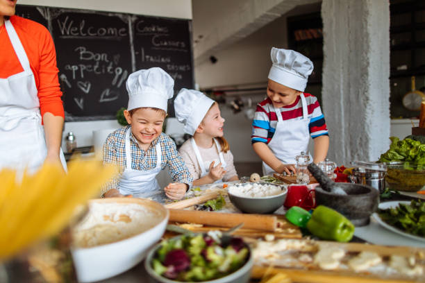 Cooking is fun! Photo of a group of children having fun during cooking class with a chef cooking class photos stock pictures, royalty-free photos & images