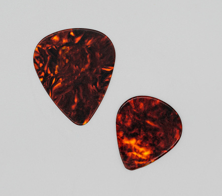 Two different sizes of brown plastic guitar plectrum isolated on white background. Guitar Picks