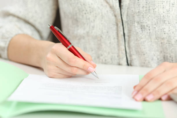 istock Closeup of a hand signing a contract on a desktop 918068446