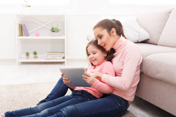 istock Little girl and her mom using a tablet at home 918072984
